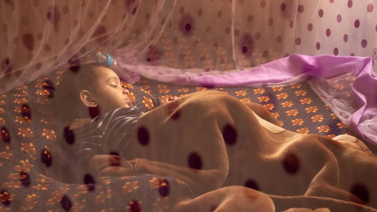 A child sleeping safely under a treated mosquito net